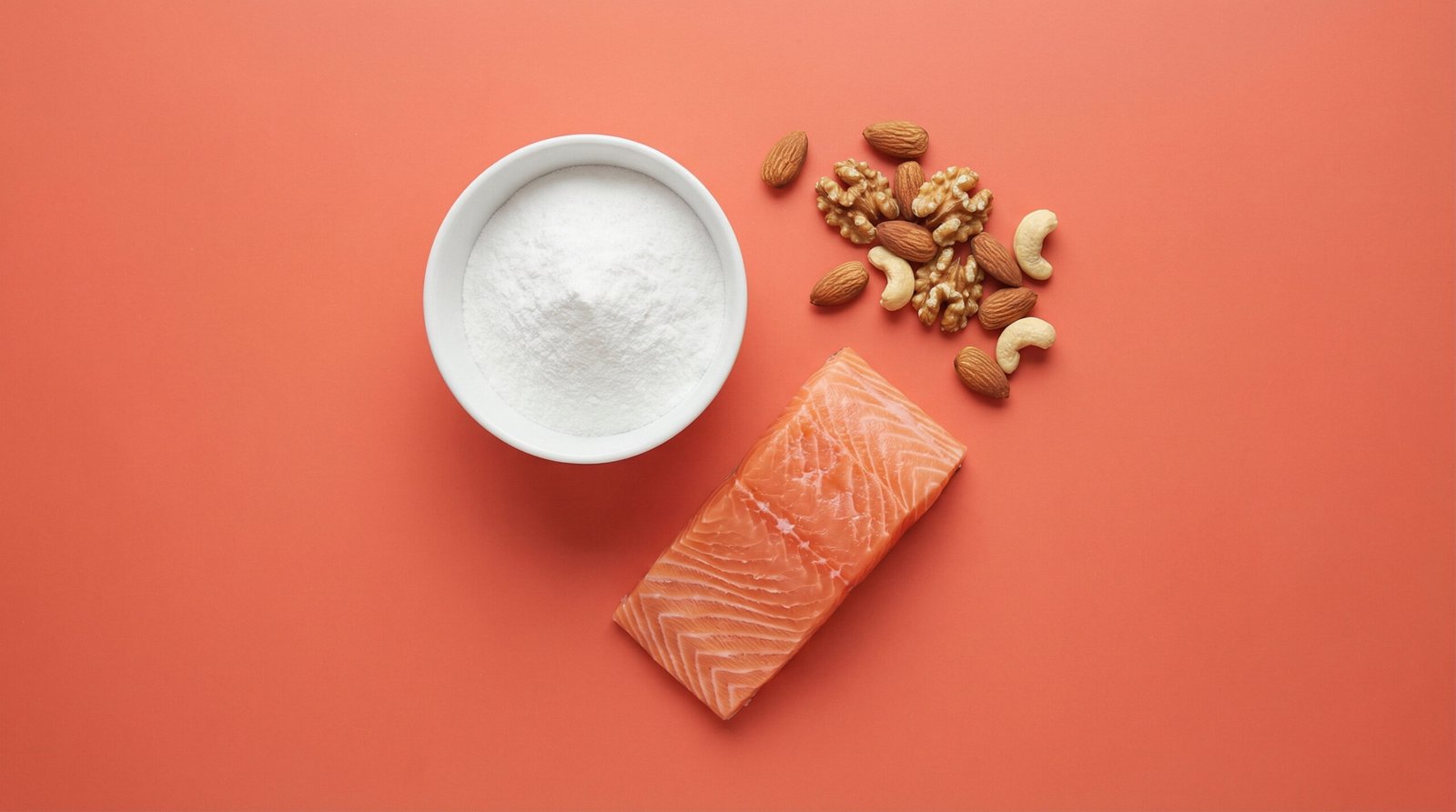 Creatine for women — overhead flatlay of creatine monohydrate powder in a ceramic bowl with salmon and mixed nuts on a coral background
