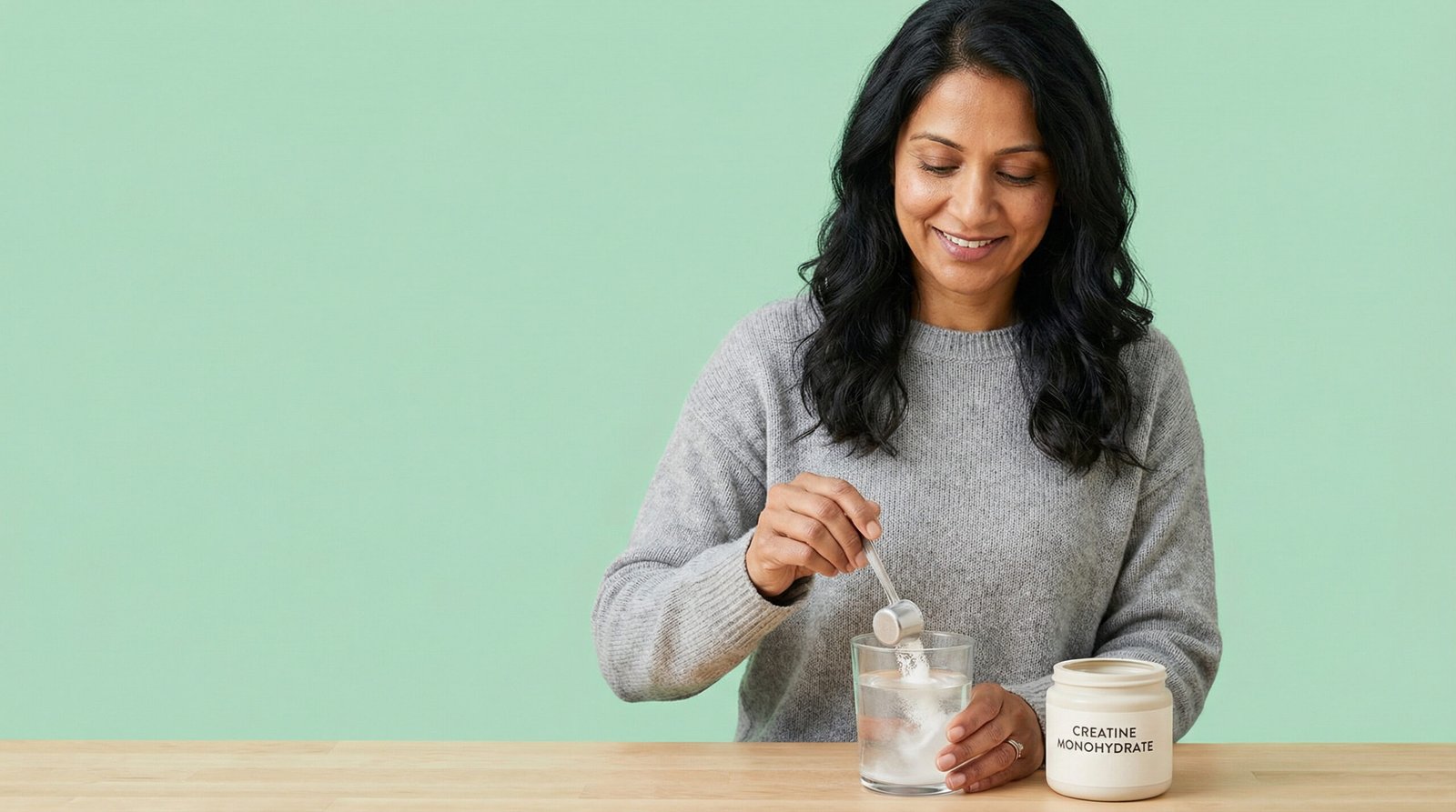 Creatine for women — South Asian woman mixing creatine powder into a glass of water as part of her morning routine