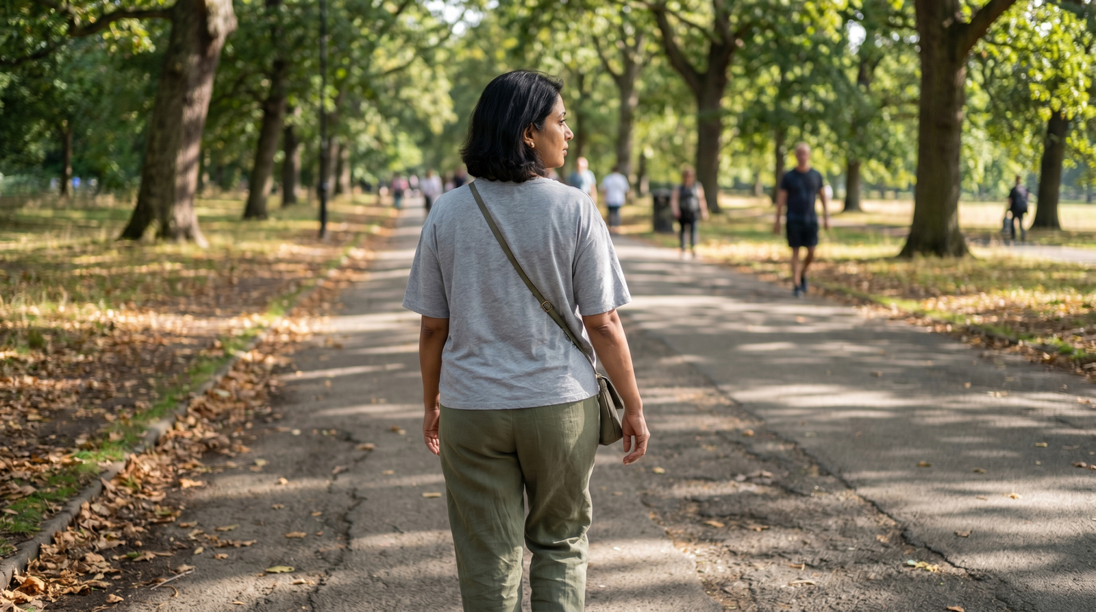 person taking an after-meal walk on a sunny park path to support glucose variability management
