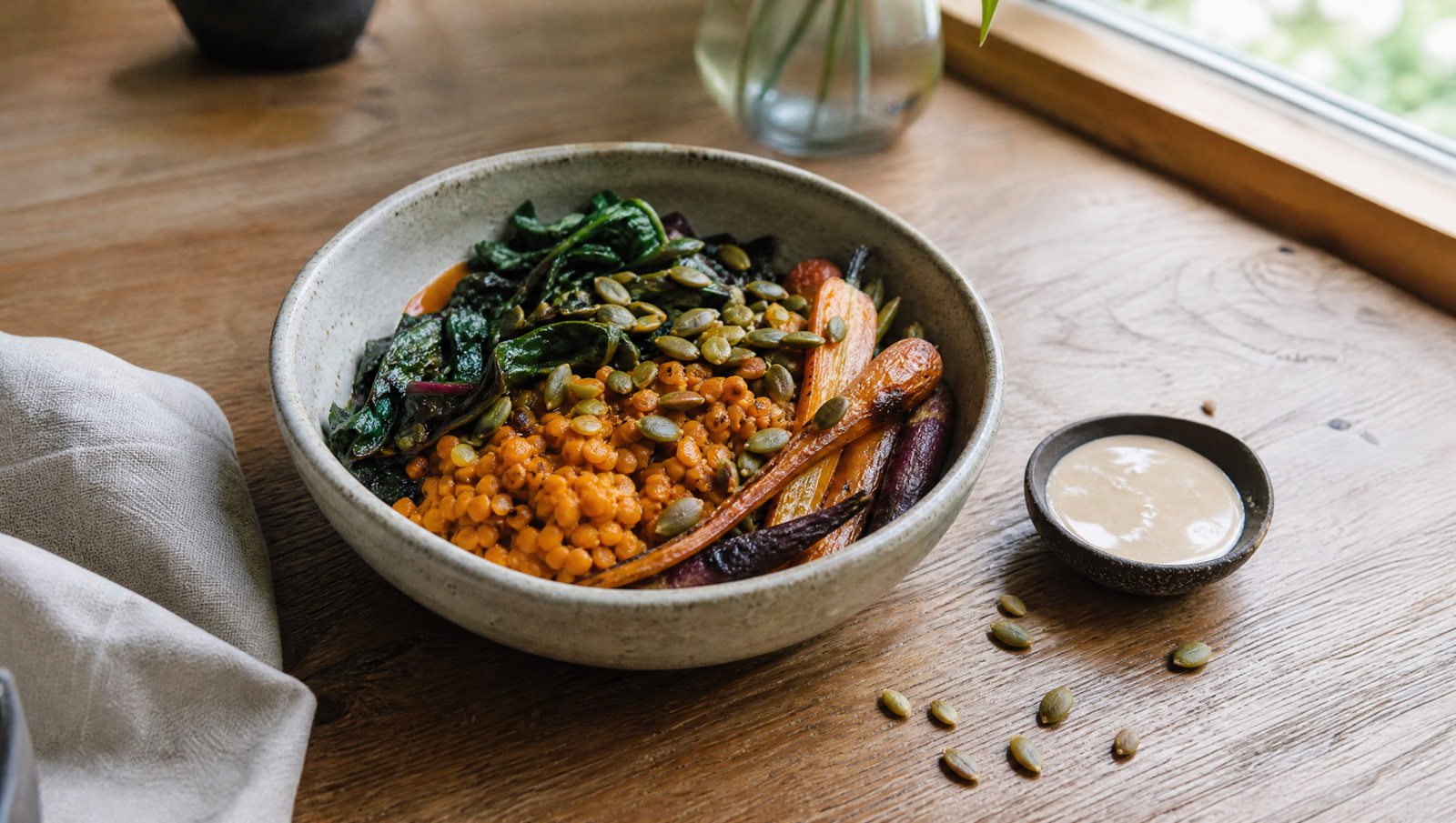 blood sugar hacks — colorful lentil bowl with roasted carrots, chard, and pumpkin seeds on a light wood table