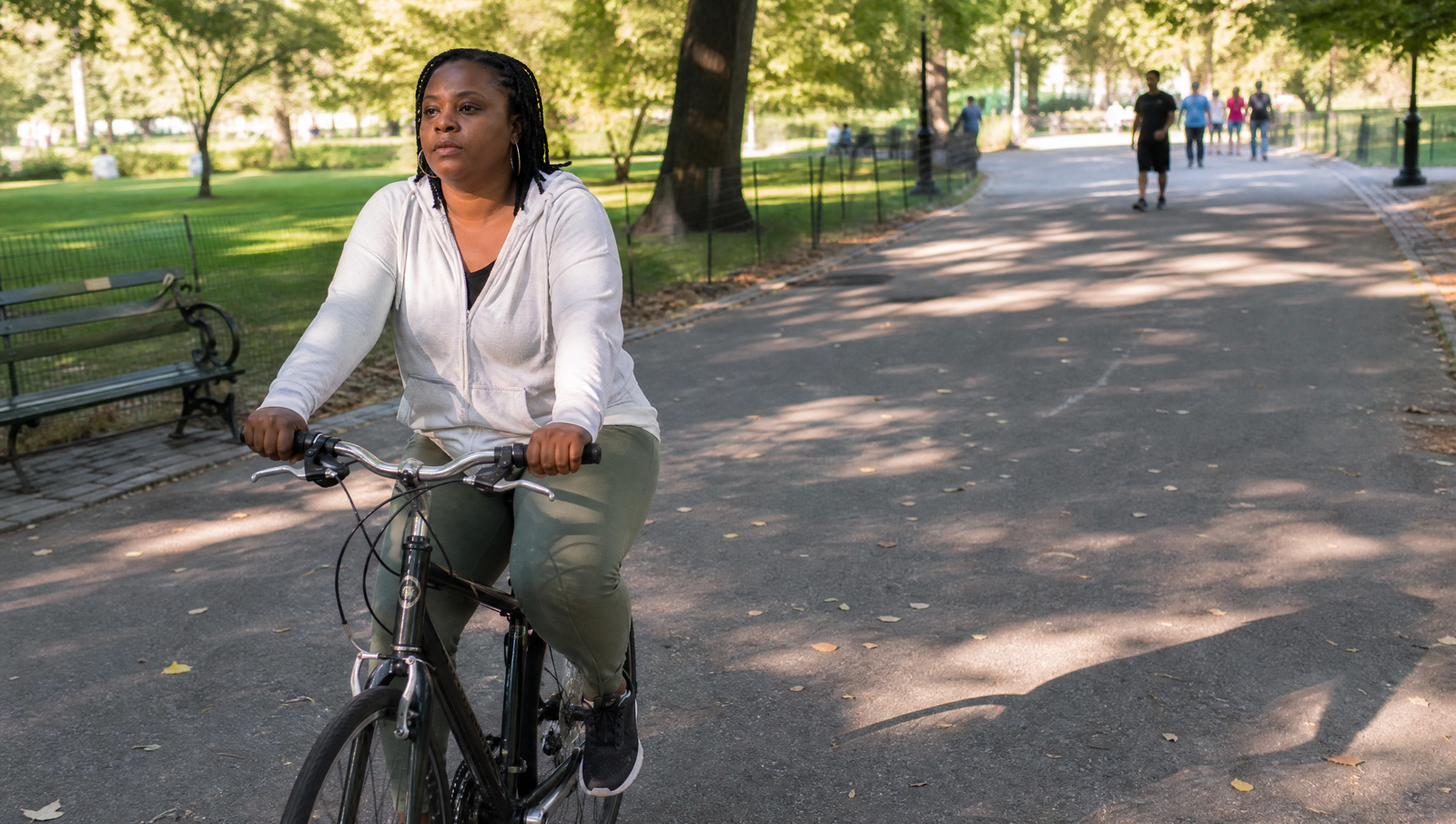 zone 2 exercise for blood sugar — woman cycling steadily on a tree-lined park path at moderate pace